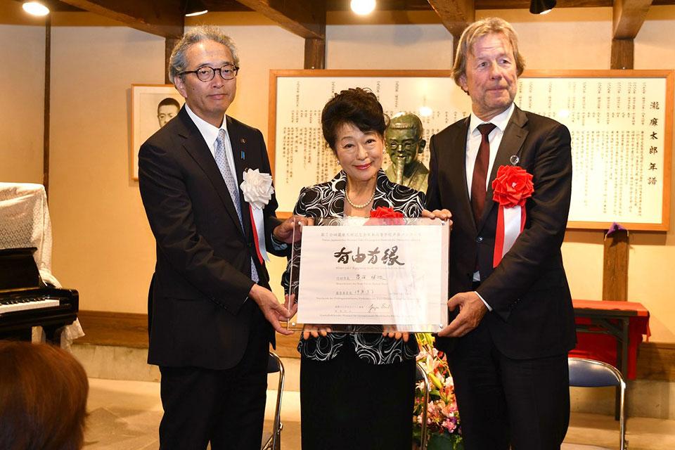 左から、首藤勝次竹田市長、伊原直子先生、ユルゲン・エアンスト事務総長が一緒にプレートを持っている写真