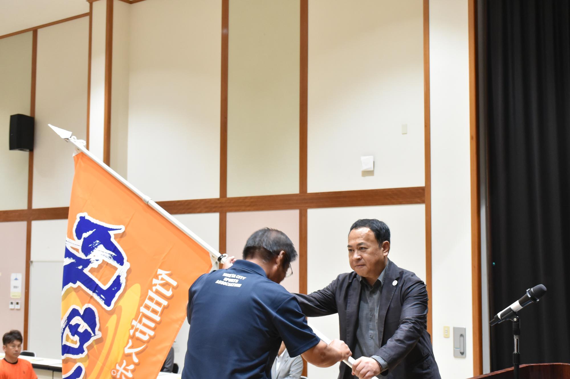 団旗推戴：土居 昌弘団長から本田 忠総監督へ