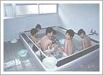 6人の男の子が大きなお風呂の湯舟に浸かっている写真