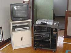 左側には棚の中にビデオデッキとその上にブラウン管テレビが置かれて、右側には音響設備が写っている写真