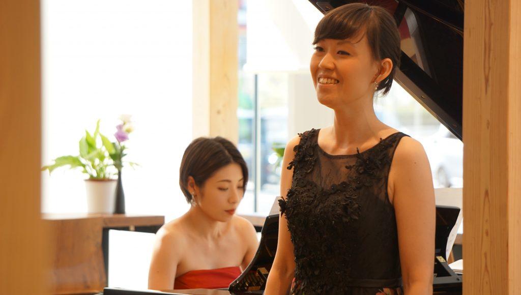 赤いドレスを着た小町さんがピアノを演奏している前で、黒いドレスを着て伸びやかに歌う田島さんの写真