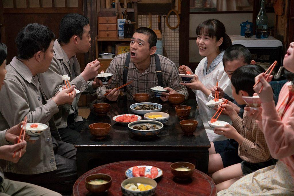 博多華丸を中心に家族みんなで食卓を囲む映画の一場面の写真